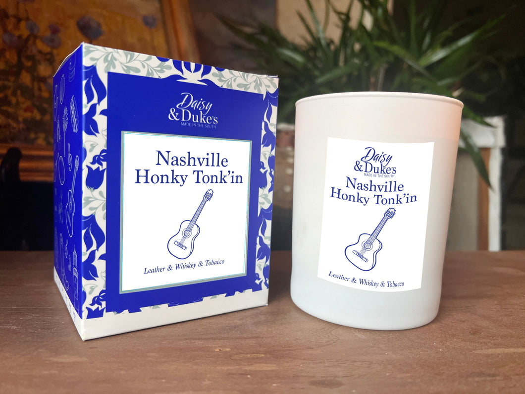 Candle and packaging of Daisy & Dukes Nashville Honky Tonkin' on a wooden surface.